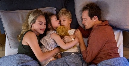 Family laying on mattress together