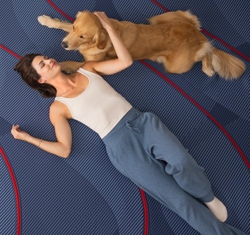 A woman and dog laying on a Posturepedic Elite Hybrid mattress
