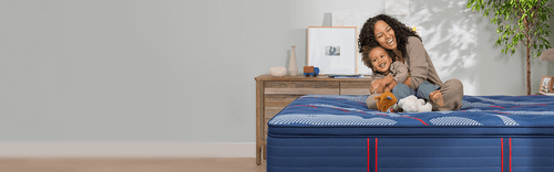 Woman and child sitting on a Elite spring mattress with a pillow top