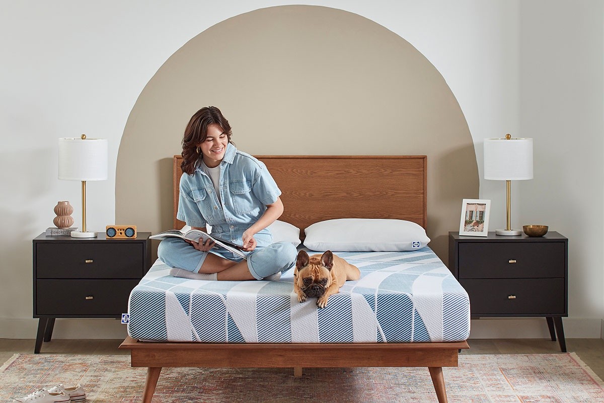 a young lady sitting on a dreamlife mattress with her dog
