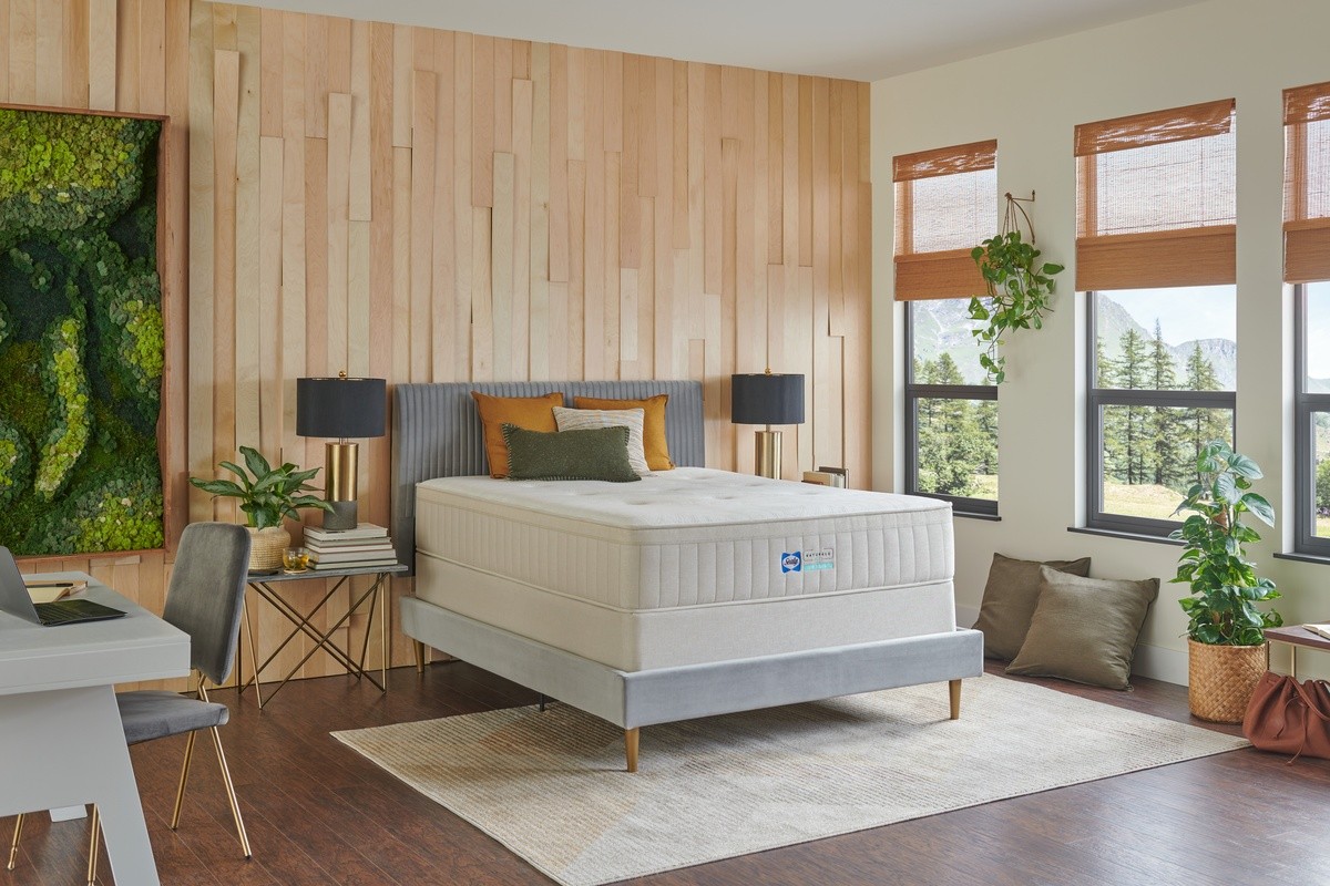 A Naturals mattress on a bed frame in a styled room with wood paneled walls