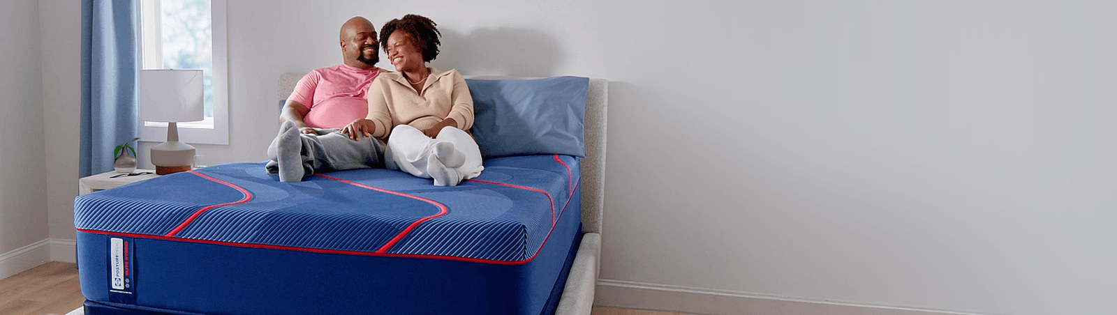 Man and woman laying on a Posturepedic Elite Hybrid mattress in a styled room