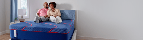Man and woman laying on a Posturepedic Elite Hybrid mattress in a styled room